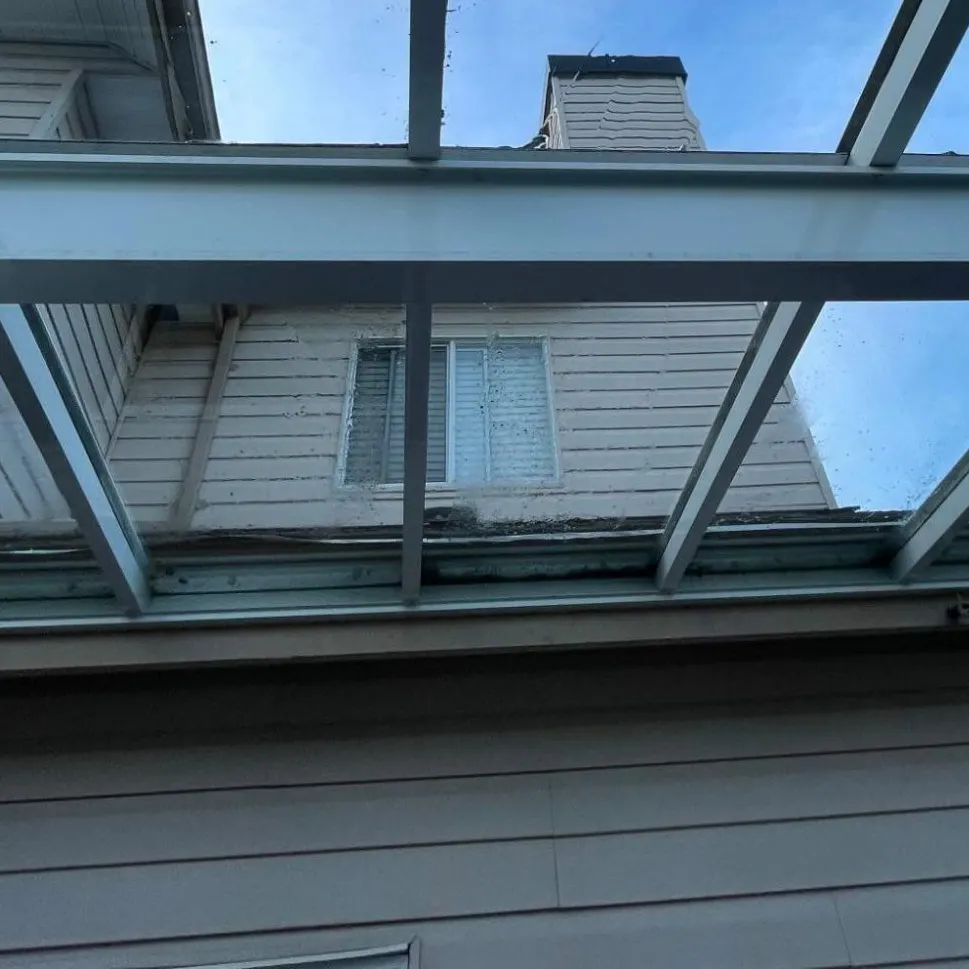 The same glass patio cover after cleaning, the house and a clear blue sky sharp through the panels.