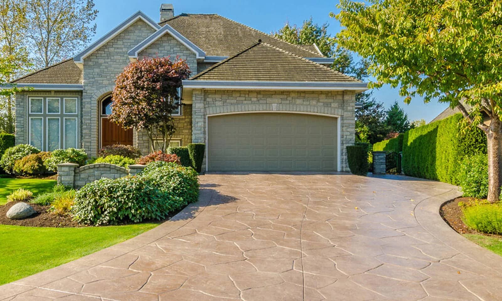 Concrete and asphalt sealing: a sealed stamped-concrete driveway sweeping up to the garage of a suburban home.