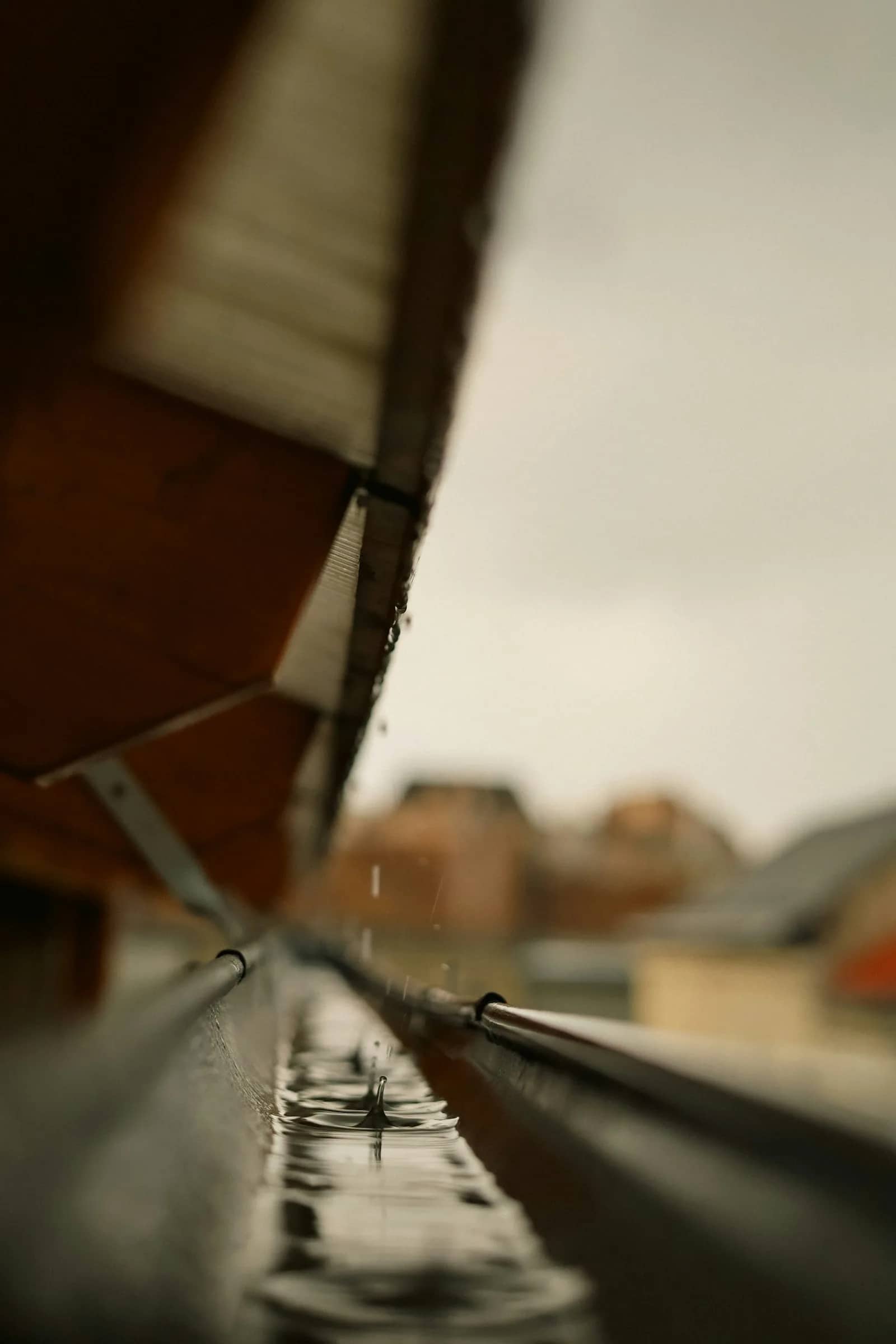 Gutter cleaning: a close view of a gutter bracket and the joint where the channel meets the fascia board under the roof edge.