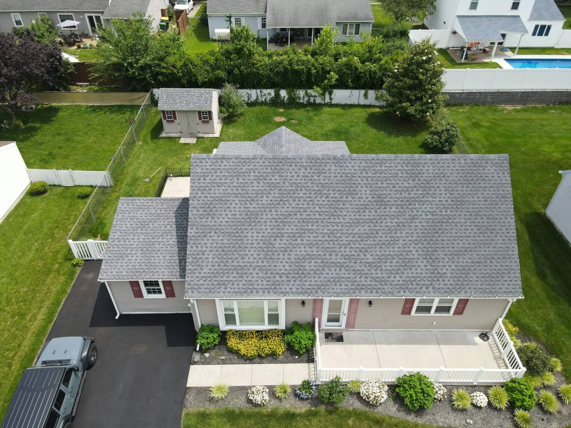 A suburban house seen from above, its grey shingle roof even in colour across every course from ridge to eaves.