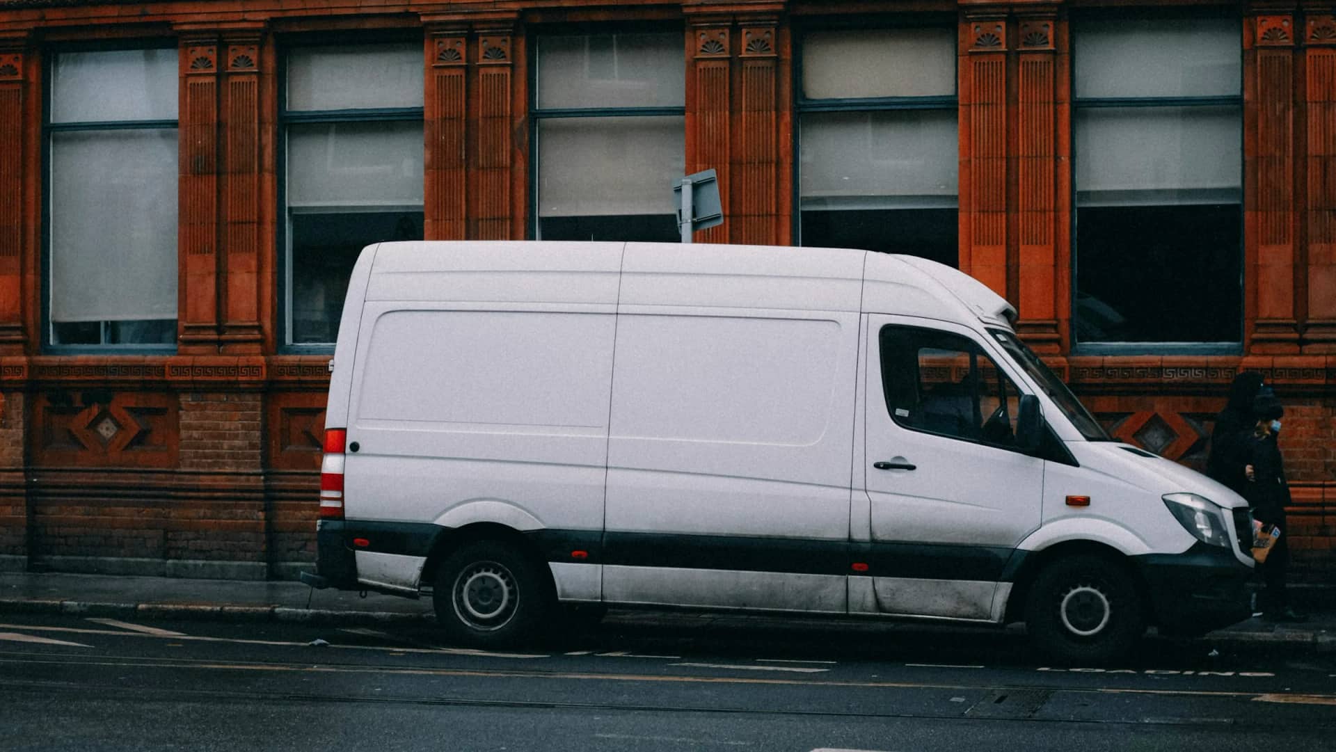A white panel van of the kind RainCity works out of, parked at the kerb outside a brick building.