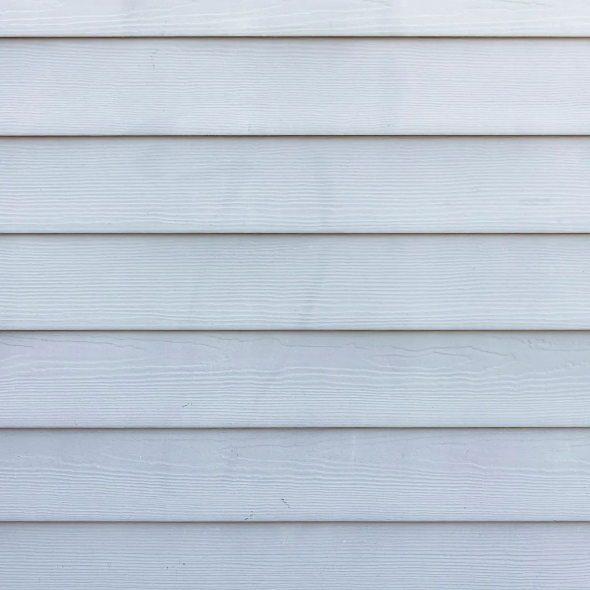 Close-up of white lap siding, the boards even in colour with no green or grey streaking.