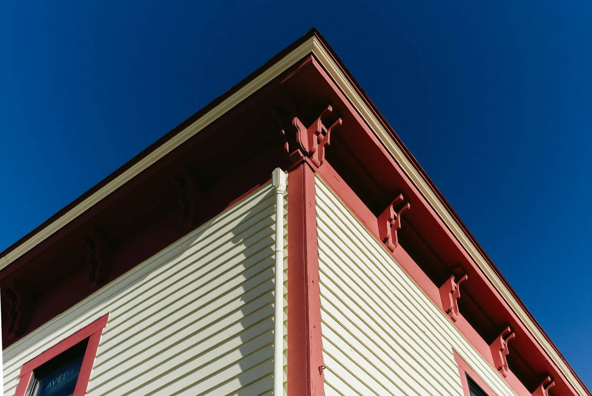 The corner of a house against a clear sky, the siding running even in colour into the soffit above with no streaking anywhere along the run.