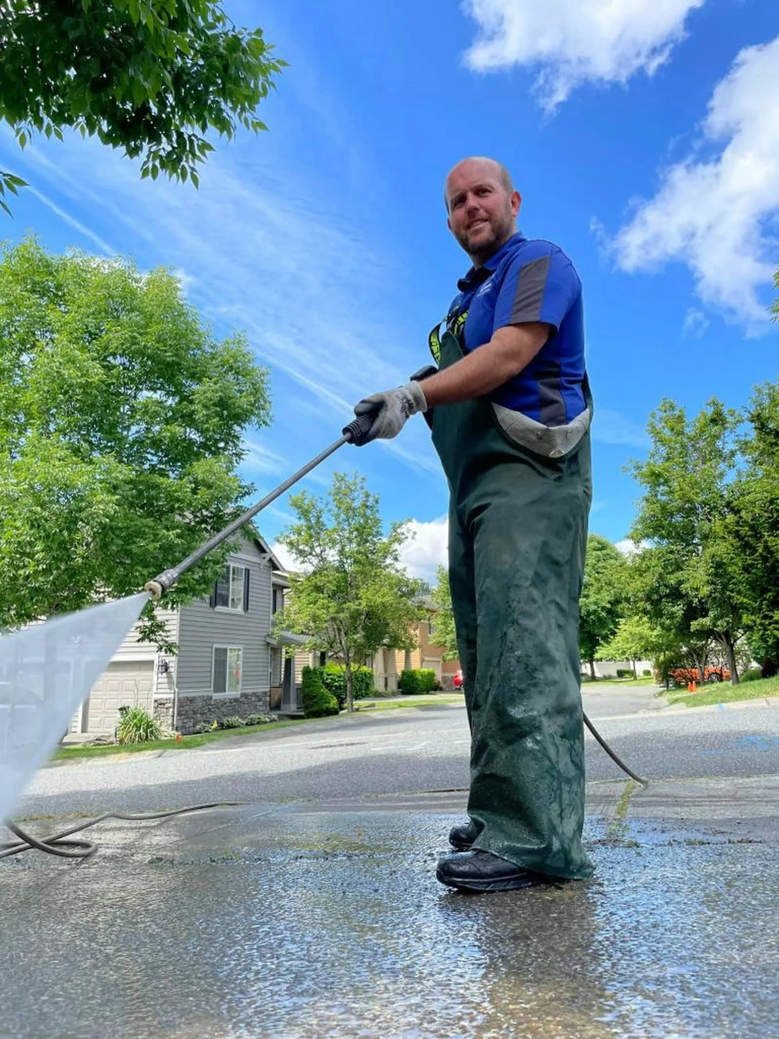 Soft washing: an operator holding a lance at waist height and laying a wide, soft fan of solution across the elevation of a house.